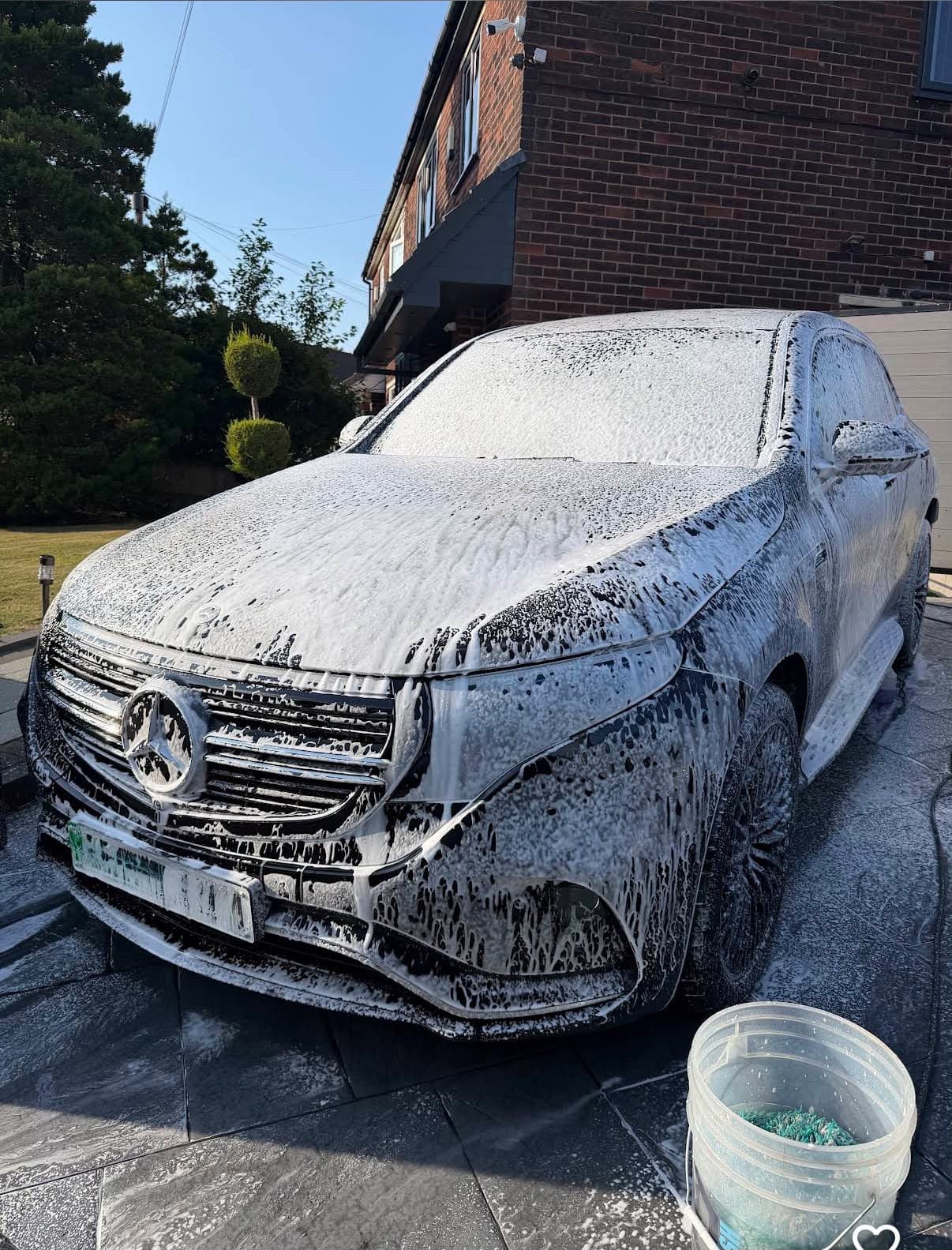 A Mercedes covered in thick snow foam during a mobile wash